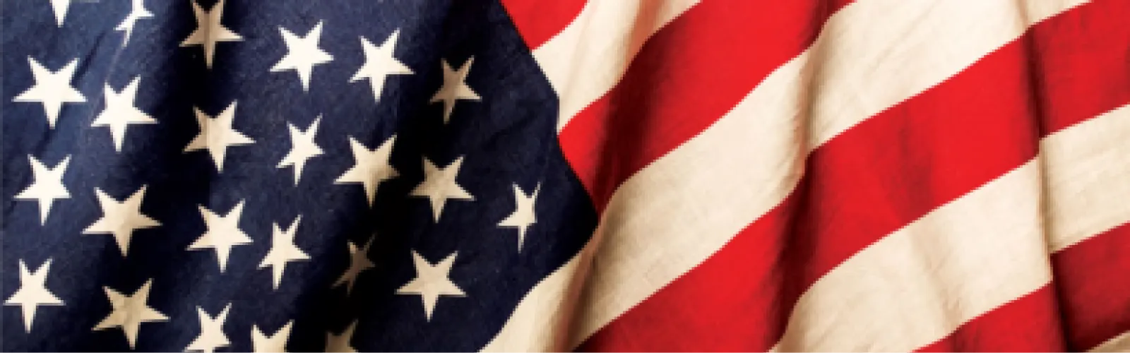 Closeup of an American Flag with white stars on blue background and red and white stripes. 